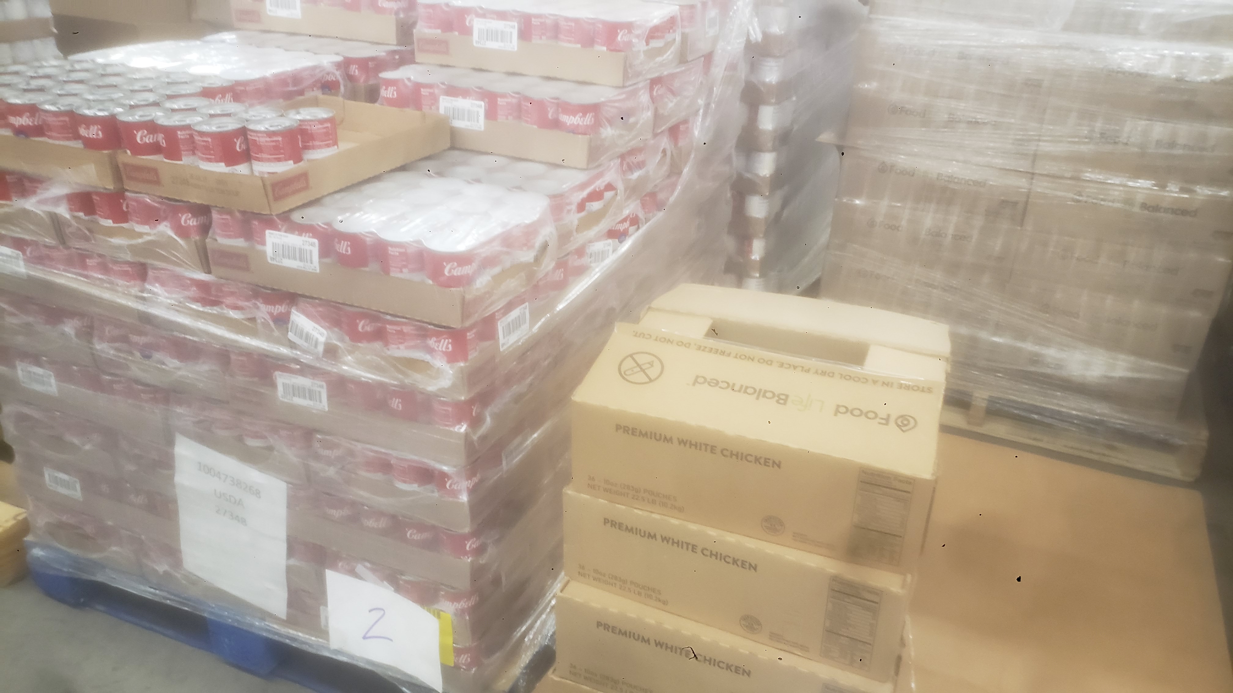 Pallets of canned soup in trays and boxes of chicken in pouches.